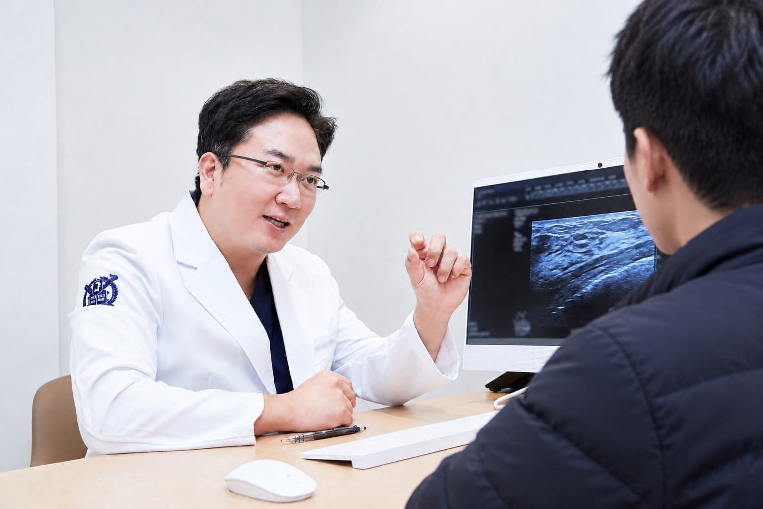 초음파 화면을 보여 주며 남성 환자에게 설명하는 정준우 원장
